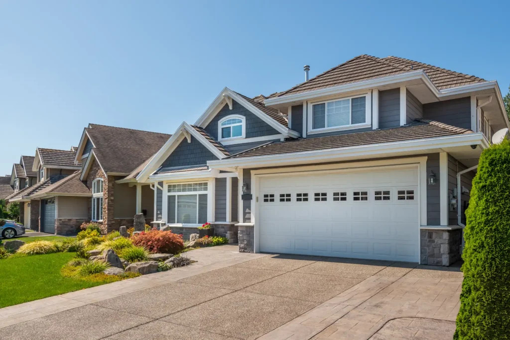 Row of modern suburban houses with a paved driveway on a sunny day.